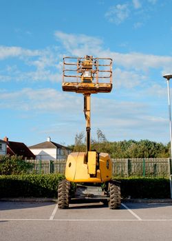 Telescopic boom lift raised up on blue sky background delivered to construction site ready to be used by steel frame erectors, roofers and painters