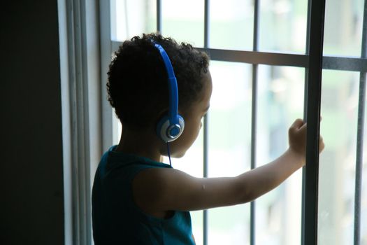 salvador, bahia, brazil - september 30, 2021: child is seen wearing earphone in apartment window during coronavirus pandemic period in Salvador city.