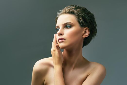 Glamorous portrait of young woman on gray background. Young sensual model girl pose in studio.