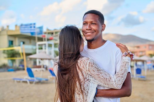 Happy young couple hugging, man's face close up. Multiculturial couple, african american man looking to side on summer beach, relationship, love, happiness, people, family, tourism, travel