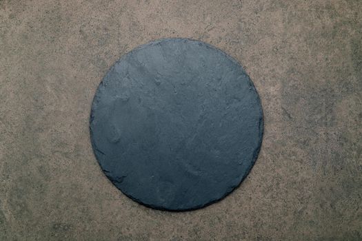 Empty pizza platter for homemade baking set up on dark concrete. Food recipe concept on dark stone background texture with copy space. 