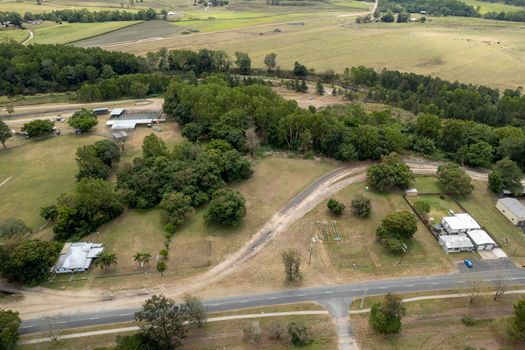 Aerial perspective of small township showing cattle yards, show ring and homes bordered by a creek and the highway. Finch Hatton, Queensland, Australia.