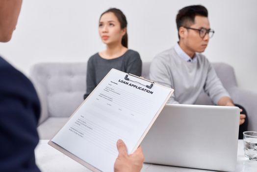 Young angry couple of cheated investors holding papers arguing with male real estate agent, defrauded property purchasers protecting their rights, too high interest rate of banking loan or mortgage