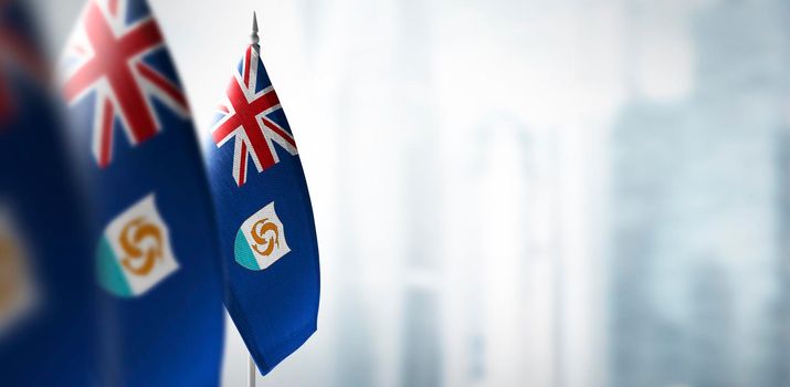 Small flags of Anguilla on a blurry background of the city.