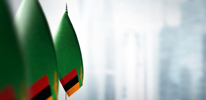 Small flags of Zambia on a blurry background of the city.