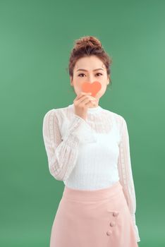 Asian Woman holding paper heart shaped card over green background. Valentine day concept.