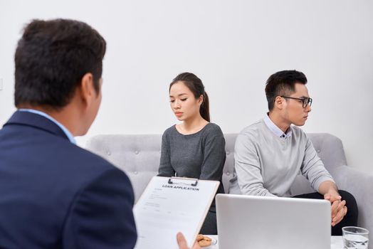 It is not my fault! Displeased young man talking to psychiatrist and gesturing while his wife sitting near him and keeping arms crossed