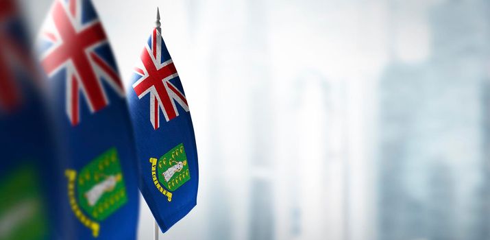 Small flags of British Virgin Islands on a blurry background of the city.