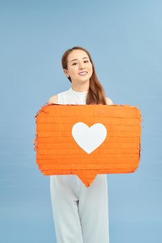 heerful young female in lilac and white clothes holding in hand red speech bubble with heart icon