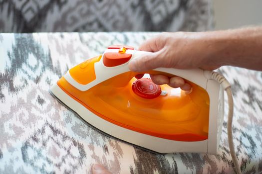 A man ironing linen with an electric iron on an ironing board. Help around the house.