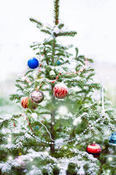Blurred, defocused christmas tree background with holiday decorations, snow and bokeh.