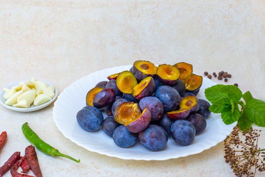 Cooking hot plum sauce. Ingredients for Tkemali on the table - plums, garlic, pepper, mint.