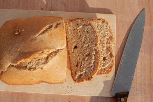 Homemade baked goods. The bun is freshly baked on a cutting board, cut into slices with a large knife.