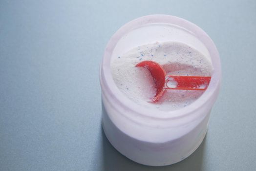 Washing powder in plastic spoon on blue background ,