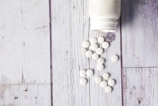 white color medical pills spilling on white background .