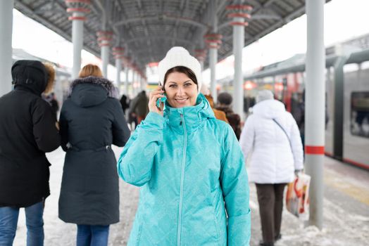 Woman talking on the phone against the background of the train in winter in Moscow, Russia