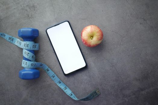 smart phone , dumbbell and apple on black background