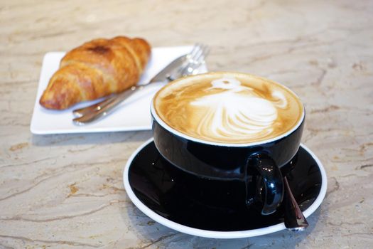 a cup of late coffee with flower shape design on top at cafe .