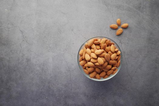 top view of almond nuts in a bowl on black background .