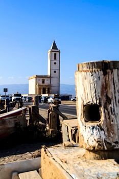 Cabo de Gata, Almeria, Spain- September 3, 2021:Wooden tie point at Las Salinas beach in Cabo de Gata-Nijar natural Park. Beautiful church in the background.