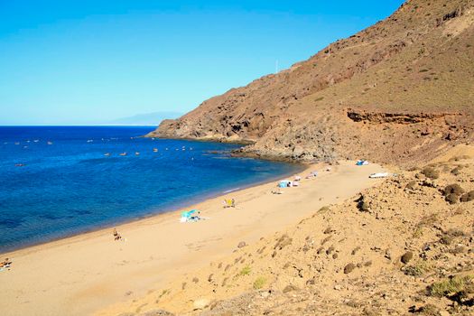 Cabo de Gata, Almeria, Spain- September 3, 2021:People enjoying and sunbathing at the Beautiful Corralete beach on a sunny day of summer