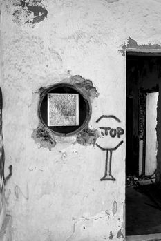 Rodalquilar, Almeria, Spain- September 7, 2021: Abandoned house with a painted stop sign and circular and a square window photographed symmetrically