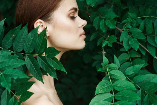 smiling woman skin care bare shoulders green leaves nature close-up. High quality photo