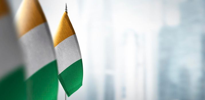 Small flags of Cote dIvoire on a blurry background of the city.