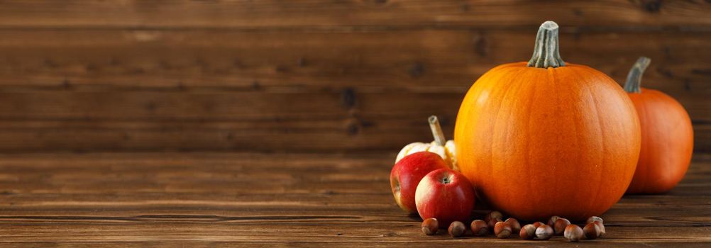 Wood background with pumpkins, apples and nuts. Copy space for text