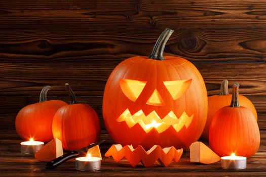 Carving of Halloween pumpkin in progress, candles pieces and cutting knife on wooden background