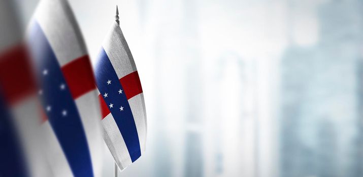 Small flags of Netherlands Antilles on a blurry background of the city.