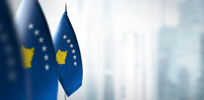 Small flags of Kosovo on a blurry background of the city.