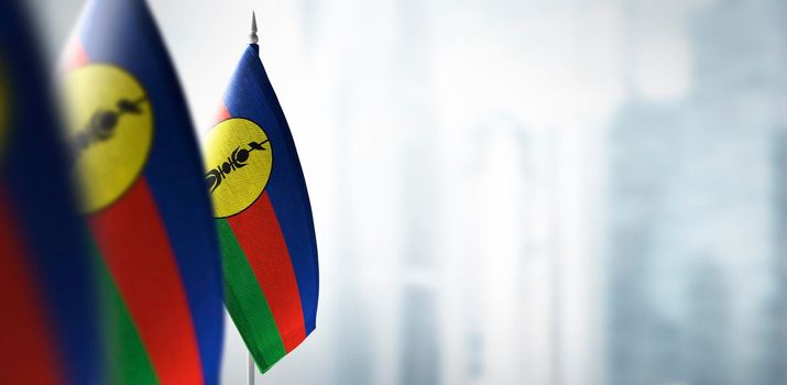 Small flags of New Caledonia on a blurry background of the city.