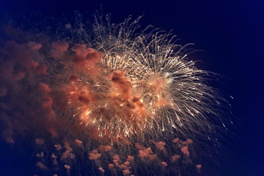 Blurred multicolored fireworks lights against the dark night sky. Festive fireworks. Light defocus
