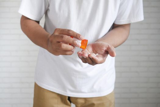 man's hand with pills spilled out of the container .