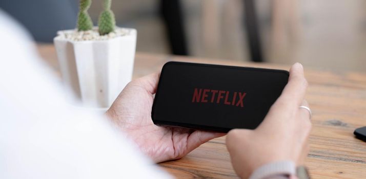 CHIANG MAI, THAILAND, AUG 2 2021 : Woman hand holding Smart Phone with Netflix logo on Apple iPhone Xs. Netflix is a global provider of streaming movies and TV series..