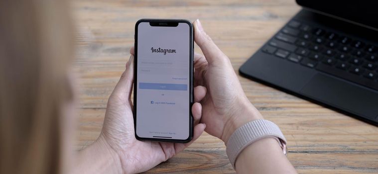 CHIANG MAI, THAILAND - SEP 24, 2021: A woman holds Apple iPhone X with Instagram application on the screen. Instagram is a photo-sharing app for smartphones..