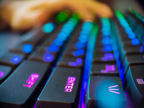 Gamer keyboard with neon backlight macro defocused close up. Online games and virtual reality concept background. High quality photo