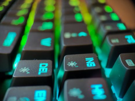 Gamer keyboard with neon backlight macro defocused close up. Online games and virtual reality concept background. High quality photo