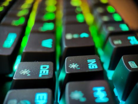 Gamer keyboard with neon backlight macro defocused close up. Online games and virtual reality concept background. High quality photo