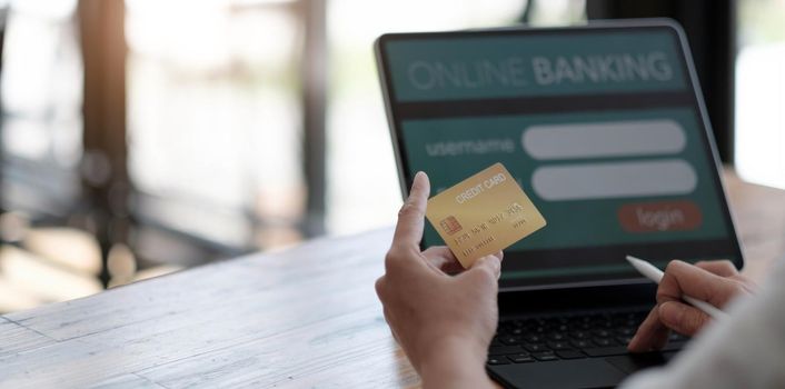 Online payment,woman's hands holding a credit card and using laptop computer for online shopping with vintage filter tone.