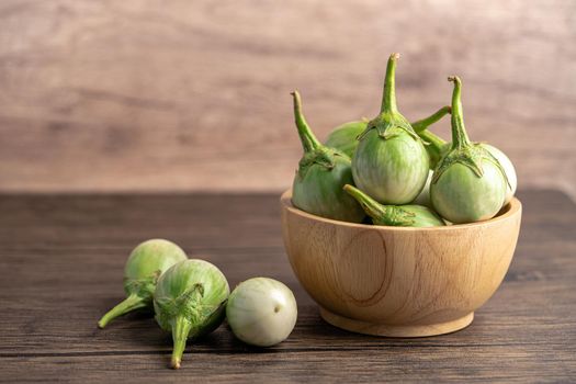 Green eggplant fresh vegetable in wooden bowl with copy space.