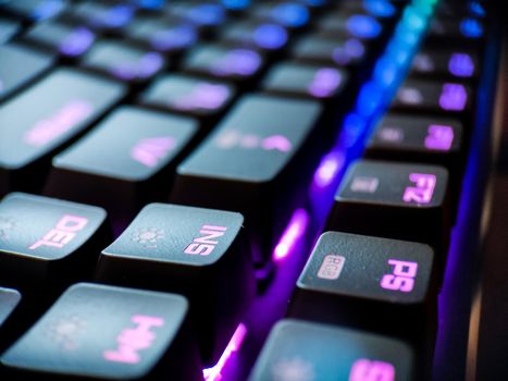 Gamer keyboard with neon backlight macro defocused close up. Online games and virtual reality concept background. High quality photo