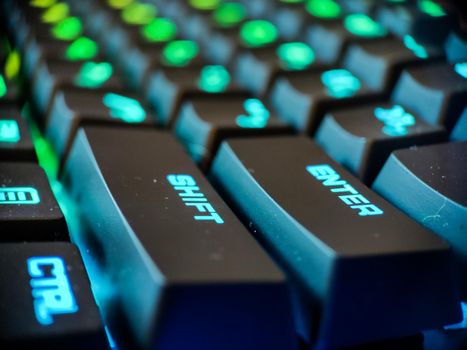 Gamer keyboard with neon backlight macro defocused close up. Online games and virtual reality concept background. High quality photo