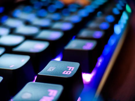 Gamer keyboard with neon backlight macro defocused close up. Online games and virtual reality concept background. High quality photo