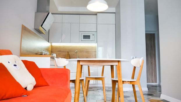 Modern kitchen interior with wooden and white elements, bright orange sofa, domestic life, home showcase interior concept