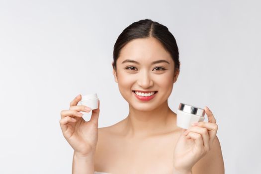 Beautiful young woman on white isolated background holding cosmetic face cream, asian.