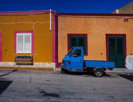 View of a typical italian Three-wheeler in the Linosa street. In the background a typical Linosa house