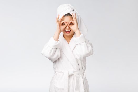 Close up of young smiling woman with finger ok gesture on eyes, isolated on white background.