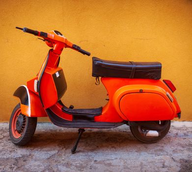 Orange Vespa, famous italian motorcycle parked in the street of Linosa
